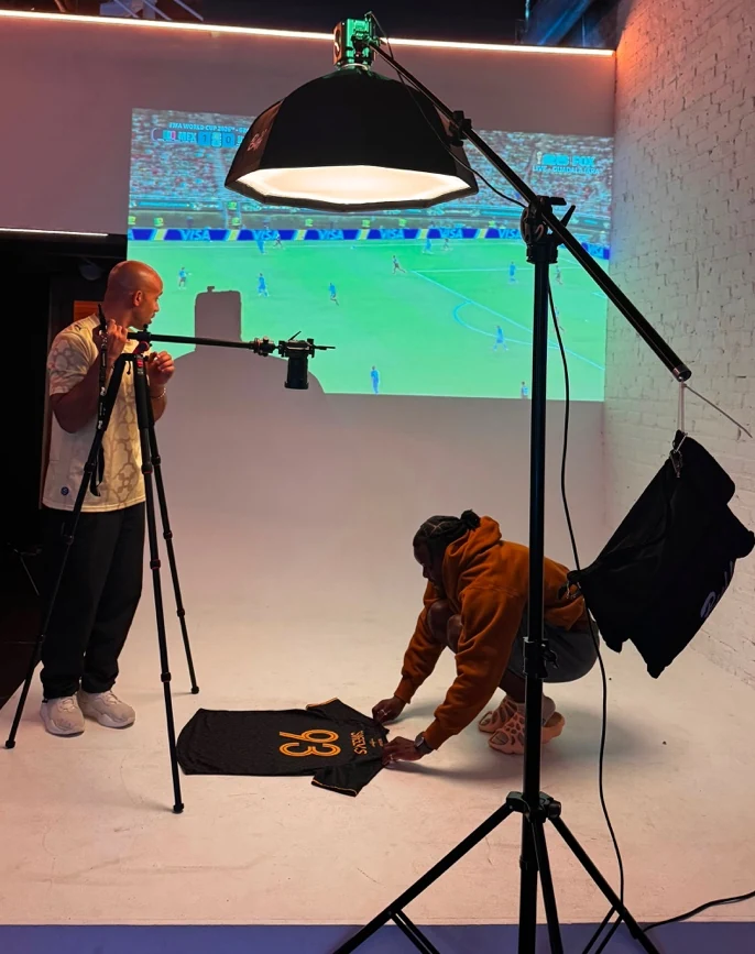 Photographer and crew at the VATAN FC studio setup with a match projected behind